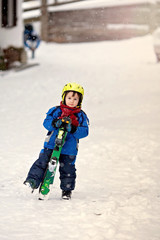 Fototapeta na wymiar Adorable little boy with blue jacket and a helmet, skiing