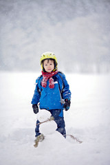 Fototapeta na wymiar Happy little boy playing in the snow while snowing, helmet