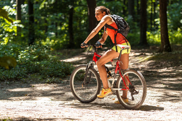 Fototapeta na wymiar Gracefully biking through the forest, a skilled female athlete enjoys the mountain bike ride.