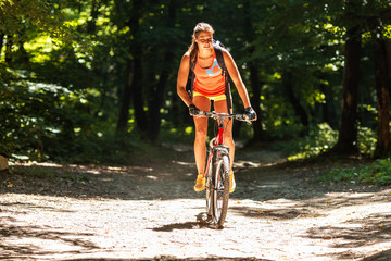 Gracefully biking through the forest, a skilled female athlete enjoys the mountain bike ride.