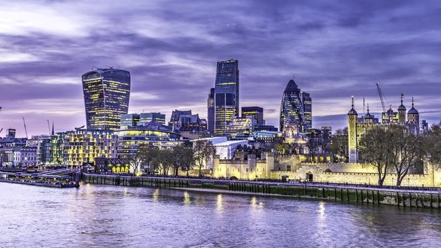 Time lapse view of the City of London skyline ant the London tower during and after sunset, transition to night with artificial lights reflected on the river Thames