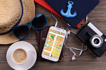 Smart phone with map gps navigation application and travel accessories on table, close-up