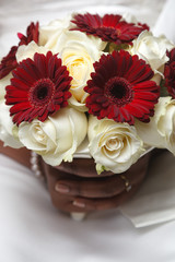 White and red wedding bouquet of roses and gerberas in the hands of the bride 