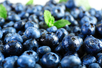 Tasty ripe blueberries with green leaves close up