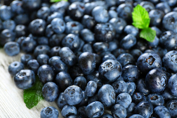 Tasty ripe blueberries with green leaves close up