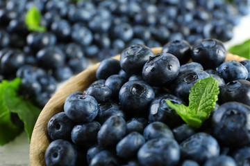 Tasty ripe blueberries with mint in bowl on table close up