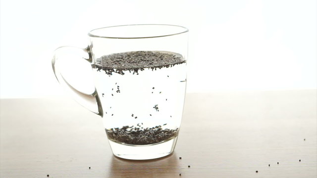 Chia seeds soak up in water glass on white background