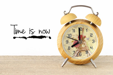Time is now words on white wall and vintage clock