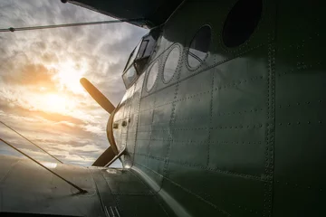 Fotobehang Oud vliegtuig vliegtuig dat de zonsondergang tegemoet vliegt