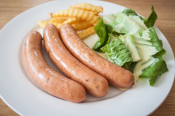 Three pieces of sausage with fresh vegetables, fried potatoes se