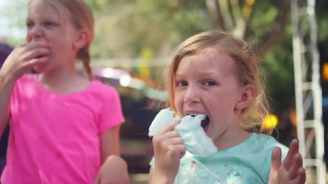 Three little girls eating cotton candy and making funny faces, in slow motion
