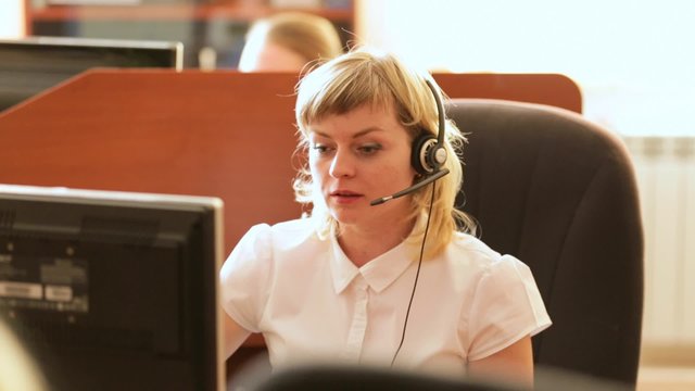 Центр поддержки пользователей. Девушка оператор разговаривает с клиентом через гарнитуру