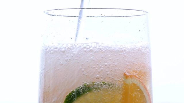 Slices of lime and orange in the glass with bubbling gas water.