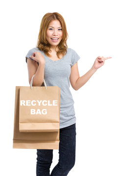 Woman finger point aside and holding shopping bag for showing re