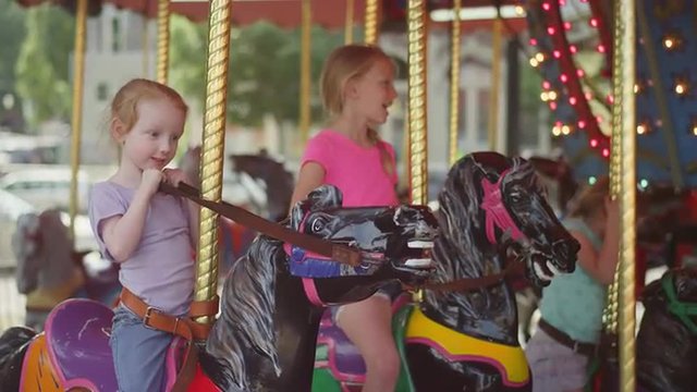 Three girls sitting on a carousel and waiting to start
