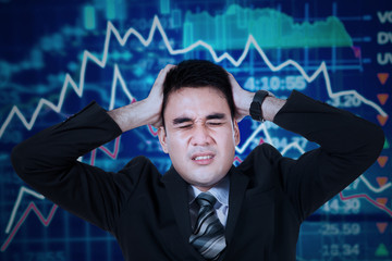 Stressful businessman with stock exchange background