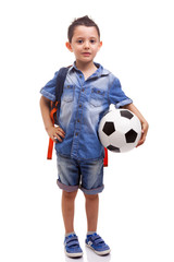 School boy standing with a soccer ball and backpack on white bac