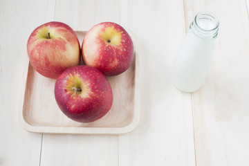 Apple and milk in bottle on wooden background