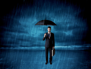 Business man standing in rain with an umbrella