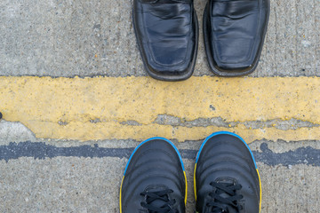 Black leather shoes and futsal shoes on road background
