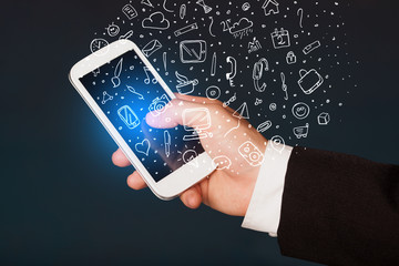 Hand holding smartphone with hand drawn media icons and symbols