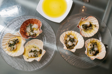 scallops topped in butter with greens on a glass plate