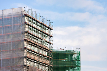 Staircase and scaffolding on a construction site,covered with mesh on sky background 