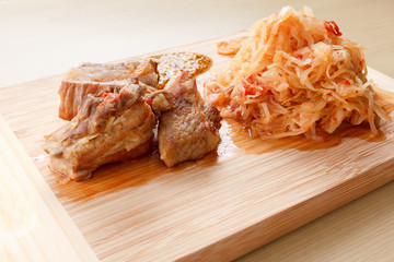 Few roasted pork ribs with tomato, carrots and cabbage on a  cutting board