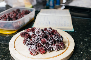 frozen blackberries with different shades of red on wood plate