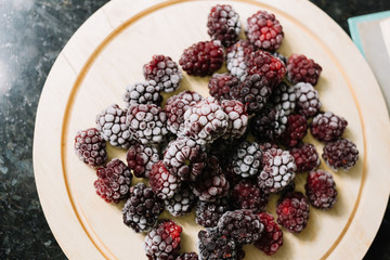 top view of frozen blackberries on wood plate
