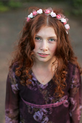 Naklejka premium Beautiful curly teenage girl in a wreath of pink and white flowers