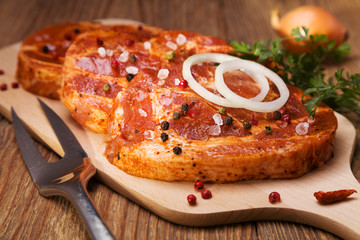 Marinated, raw pork ready for roasting on a wooden table.
