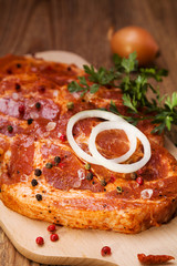 Marinated, raw pork ready for roasting on a wooden table.