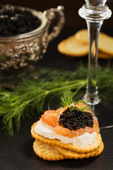 Black caviar on crackers with salmon and cream cheese, served wi