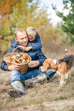 Father and son rest on forest glade after mushrooms pick