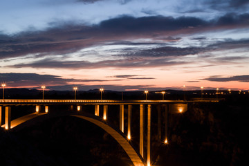 bridge with  literate street lamps against a colored sky