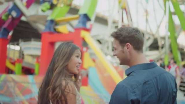 A couple taking selfies in front of a ferris wheel
