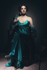 Retro 1920s woman sitting in chair holding champagne glass.
