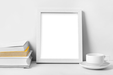 white desk with blank photo frame, books, and coffee cup
