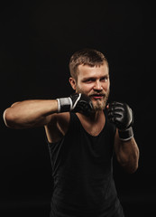 Naklejka na ściany i meble Athletic bearded boxer with gloves on a dark background