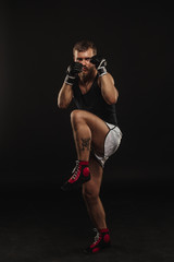 Athletic bearded boxer with gloves on a dark background