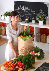 Young woman holding grocery shopping bag with vegetables