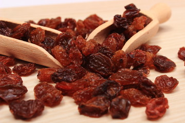 Brown raisins with spoon on wooden table, healthy eating