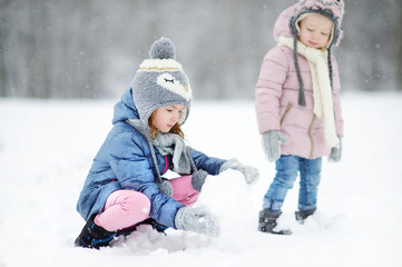Fototapeta na wymiar Two funny adorable little sisters in winter park