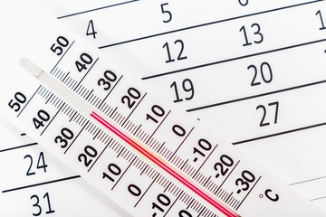 Classic thermometer sitting on a calendar sheet