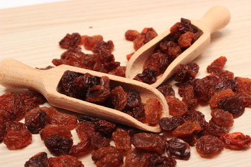 Brown raisins with spoon on wooden table, healthy eating
