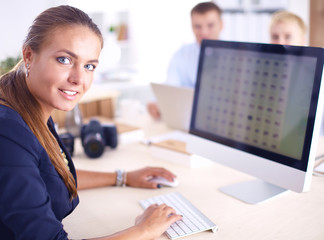 Young woman working in office, sitting at desk, using laptop