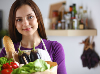 Young woman holding grocery shopping bag with vegetables