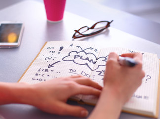 Young woman writes to diary on a white table