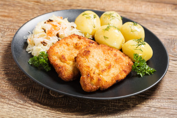 Fried pork chop in breadcrumbs, served with boiled potatoes and